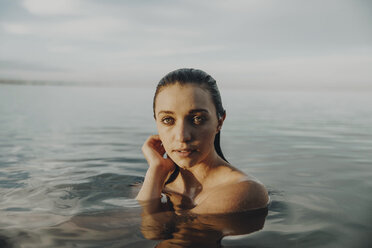 Porträt einer selbstbewussten jungen Frau, die im See schwimmt, gegen den Himmel - CAVF50992