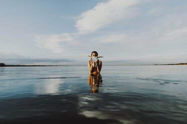 Junge Frau mit Tierschädel im See stehend gegen den Himmel - CAVF50994