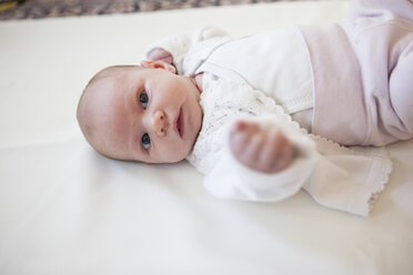 Portrait of baby girl lying on blanket - JLOF00255