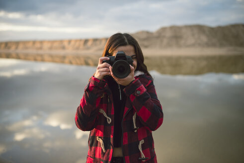 Junge Frau fotografiert mit Kamera am Strand - RAEF02189