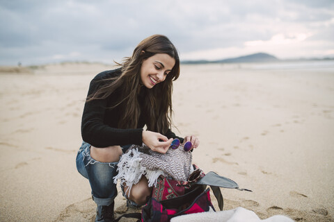 Porträt einer lächelnden Frau mit Rucksack am Strand, lizenzfreies Stockfoto