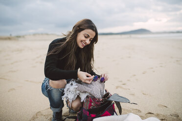 Portrait of smiling woman with backpack on the beach - RAEF02202