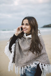Porträt einer lächelnden jungen Frau beim Telefonieren am Strand - RAEF02203