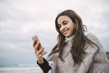 Portrait of smiling young woman looking at cell phone - RAEF02204