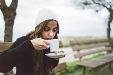 Porträt einer jungen Frau, die im Freien eine Tasse Kaffee trinkt - RAEF02215