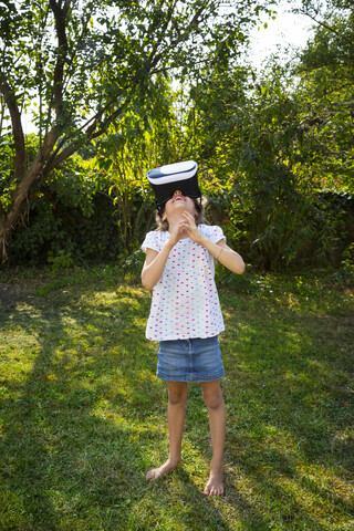 Kleines Mädchen mit Virtual-Reality-Brille im Garten, lizenzfreies Stockfoto