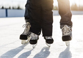 Tiefschnitt von Mutter mit Sohn beim Schlittschuhlaufen auf Schnee - CAVF51060