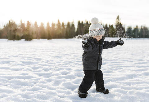 Junge spielt auf schneebedecktem Feld gegen den Himmel, lizenzfreies Stockfoto