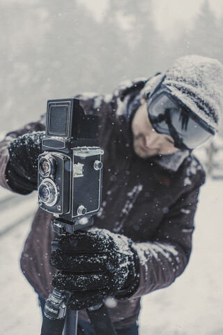 Mann beim Fotografieren im verschneiten Wald stehend, lizenzfreies Stockfoto