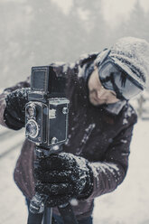Mann beim Fotografieren im verschneiten Wald stehend - CAVF51073