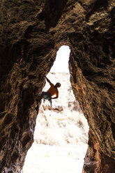 Hiker climbing rock formation at desert - CAVF51087