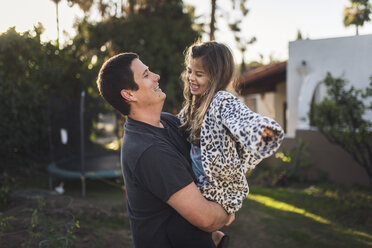 Father carrying daughter while standing in yard - CAVF51103