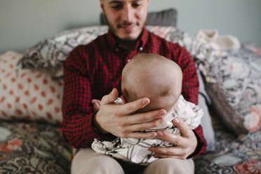 Lächelnder Vater mit Tochter, die zu Hause auf dem Bett sitzt - CAVF51115