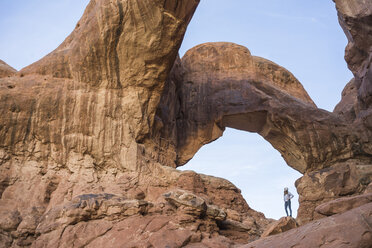 Low angle view of woman standing at rock formation against sky - CAVF51134