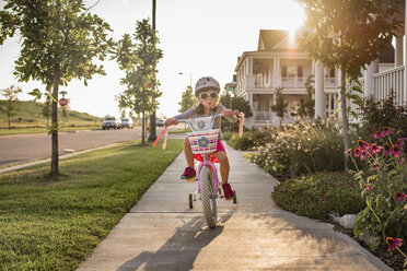 Playful girl wearing sunglasses while riding bicycle - CAVF51216