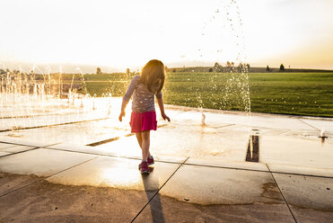 Mädchen, das nach unten schaut, während es gegen einen Springbrunnen im Park steht - CAVF51219