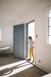 Boy looking at shadow while standing on doorway - CAVF51288