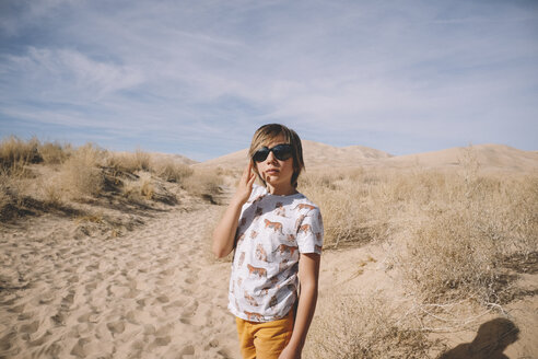 Junge mit Sonnenbrille in der Wüste an einem sonnigen Tag - CAVF51290