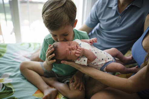 Mittelteil von Eltern mit Kindern, die zu Hause auf dem Bett sitzen - CAVF51319