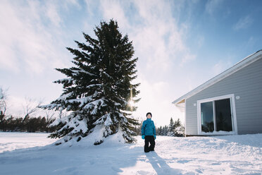 Porträt eines lächelnden Mädchens, das auf einem schneebedeckten Feld neben einem Baum im Hof steht - CAVF51333