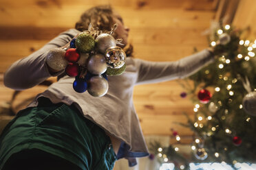 Niedriger Blickwinkel von Mädchen schmücken Weihnachtsbaum zu Hause - CAVF51342