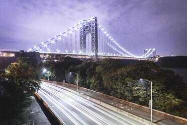 Illuminated George Washington Bridge over light trails on road against sky at dusk - CAVF51350