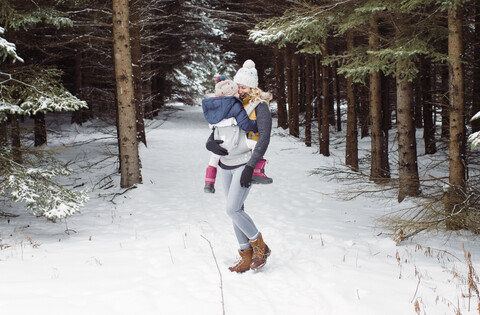 Glückliche Mutter mit Tochter im Winter im Wald stehend, lizenzfreies Stockfoto
