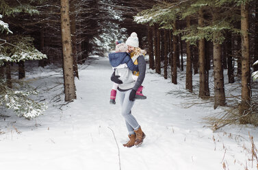 Glückliche Mutter mit Tochter im Winter im Wald stehend - CAVF51357