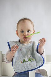 Portrait of baby girl on high chair eating mush - JLOF00271