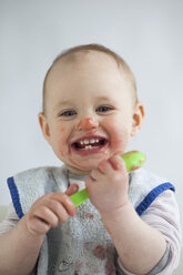 Portrait of laughing baby girl eating mush - JLOF00279