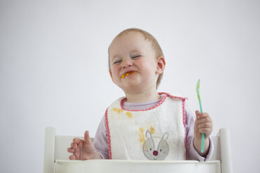 Portrait of smiling baby girl on high chair eating mush - JLOF00288