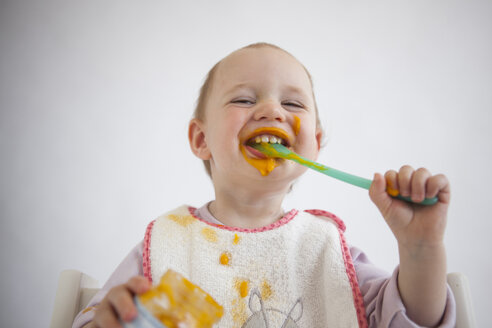 Porträt eines lustigen kleinen Mädchens, das Brei isst - JLOF00290