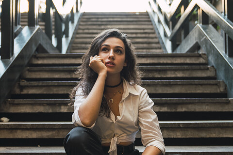 Porträt einer jungen Frau auf einer Treppe sitzend, lizenzfreies Stockfoto