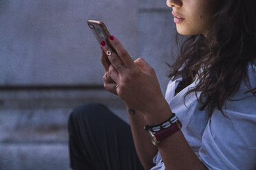 Young woman using cell phone at twilight, partial view - KKAF02835