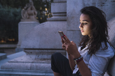Young woman using cell phone at evening twilight - KKAF02836