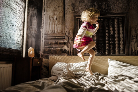 Little girl jumping on parent's bed at home having fun stock photo