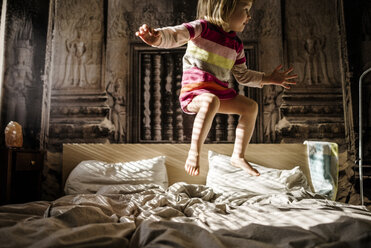 Little girl jumping on parent's bed at home - PSIF00129