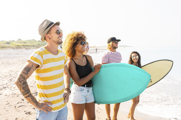 Group of friends walking on the beach, carrying surfboards - WPEF00954