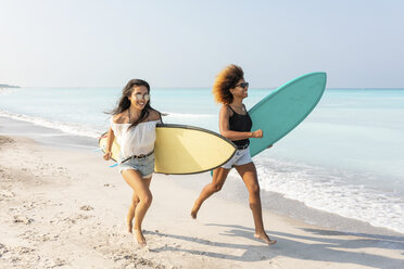Freundinnen, die am Strand laufen und Surfbretter tragen - WPEF00957