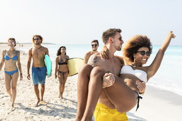 Friends walking on the beach, one man carrying his girlfriend - WPEF00990