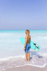 Junger Mann steht am Meer und hält sein Surfbrett - WPEF01008