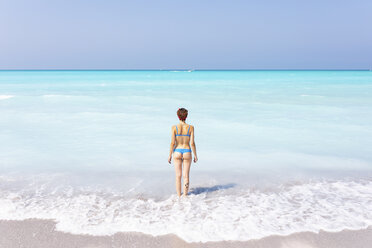 Junge Frau steht am Meer und schaut in die Ferne, Rückansicht - WPEF01036