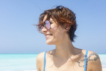 Porträt einer kopfstehenden Frau mit Sonnenbrille am Meer - WPEF01070