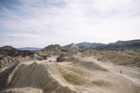 Blick aus mittlerer Entfernung auf einen Wanderer inmitten der Wüste bei bewölktem Himmel im Death Valley National Park, lizenzfreies Stockfoto