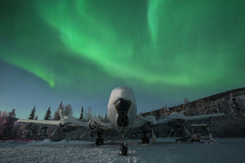 Snow covered airplane against aurora borealis stock photo