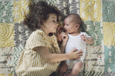 Overhead view of girl lying with baby boy on bed at home - CAVF51426