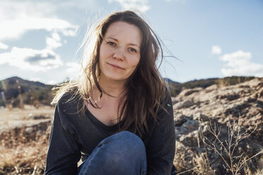 Portrait of smiling woman sitting on field against sky - CAVF51444