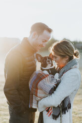 Couple carrying their puppy in woollen blanket - CUF46333