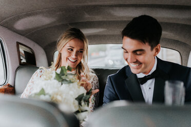 Braut und Bräutigam auf dem Rücksitz eines Autos - CUF46339