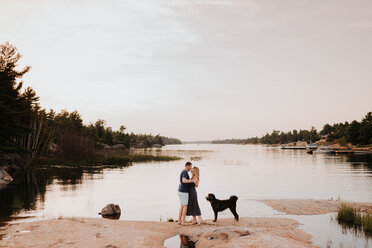 Couple enjoying view of river with pet dog, Algonquin Park, Canada - CUF46357